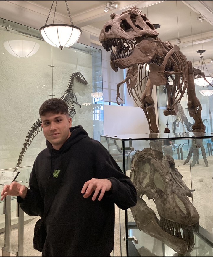David posing like a T-Rex next to a Tyrannosaurus skeleton at the American Museum of Natural History